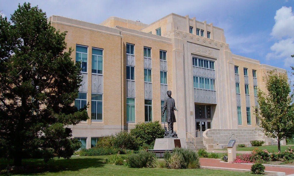 Historic government building in Portales, New Mexico, with statue. Boost your business with a Digital Marketing Company.