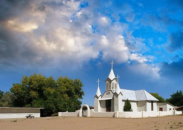 White church in Los Lunas, New Mexico, under dramatic sky. Increase visibility with a leading SEO Company.
