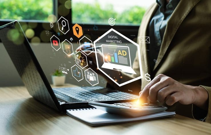 Person using a laptop with digital marketing icons hovering above the keyboard