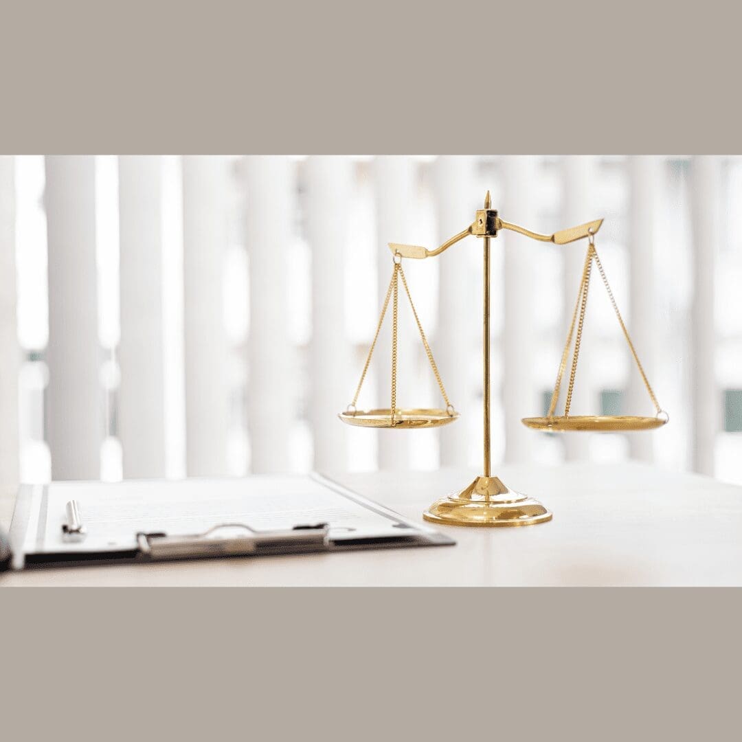 Golden scales of justice on a desk next to a clipboard