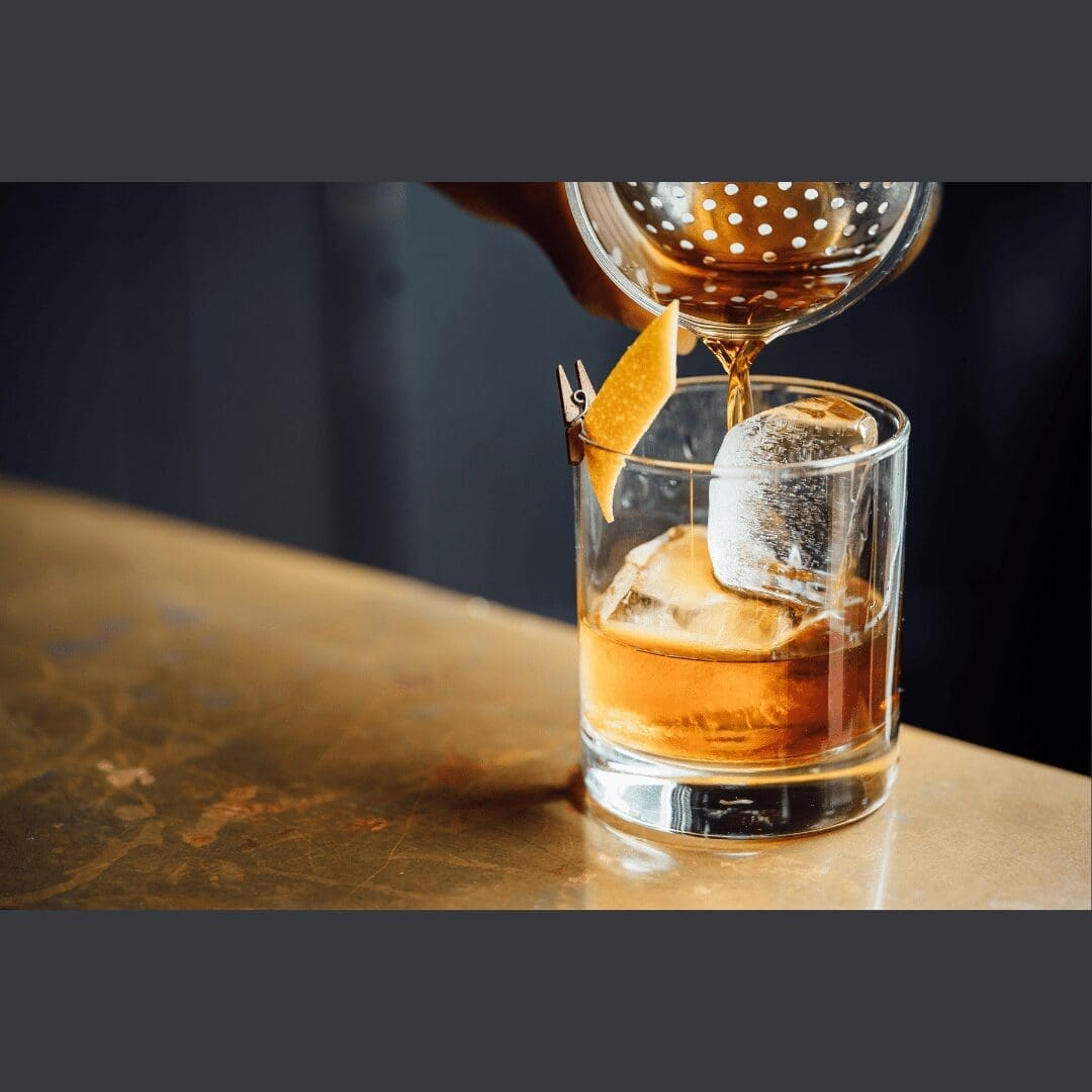 an alcoholic drink on the rocks being poured and garnished at an Albuquerque Bar