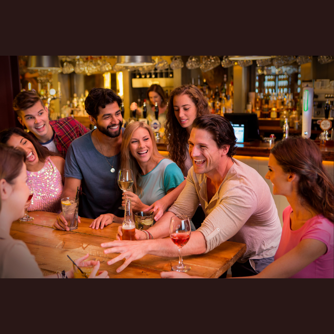 group of eight adults at an Albuquerque bar with drinks, all of them laughing and smiling